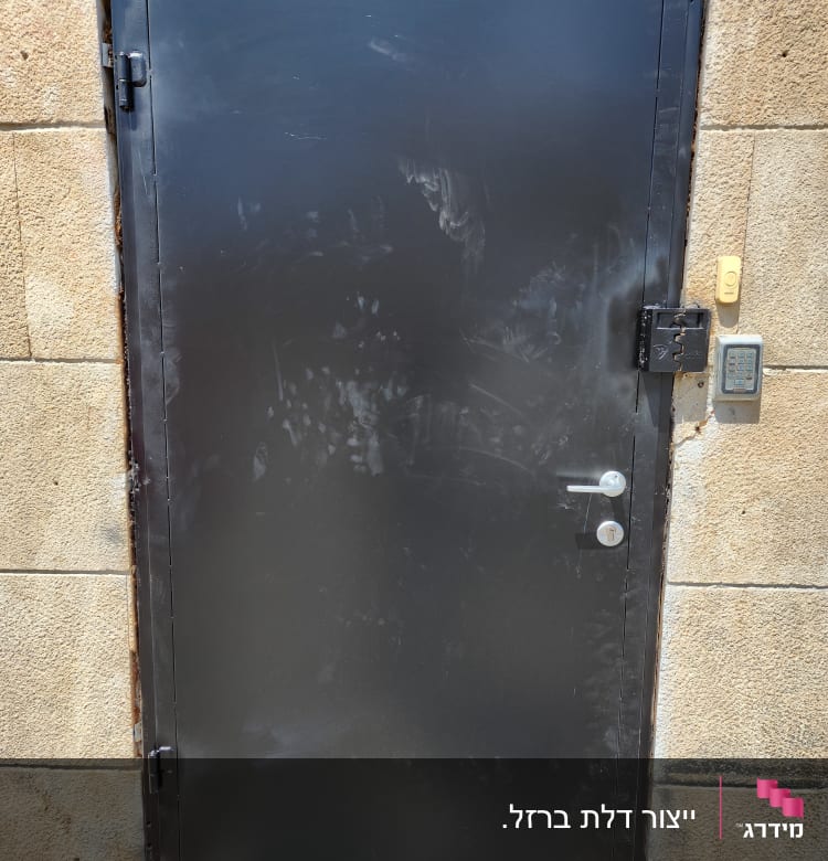 דלת מתכת שחורה עם מסגרת על קיר אבן